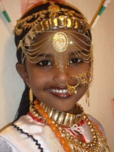 Afar girl wearing the traditional guntiino, armlets, headband, henna, and jewellery